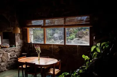 a table and chairs in a room with a window at Cueva de lujo con rio de montaña Casa cueva in Villa Cura Brochero