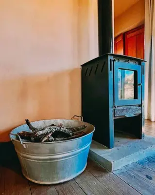 a metal tub sitting on the floor next to a stove at Cueva de lujo con rio de montaña Casa cueva in Villa Cura Brochero