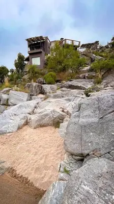 a house on top of a hill with rocks at Cueva de lujo con rio de montaña Casa cueva in Villa Cura Brochero