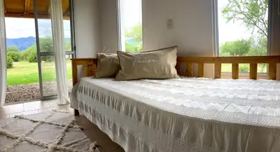 a bed in a room with a large window at Cabañas Yin y Yang in Pueblito