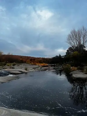 a river with rocks and trees in the background at Casa Campo Cordoba Cabalango in Cavalango