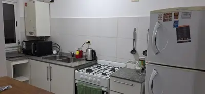 a small kitchen with a stove and a refrigerator at Departamento Lautaro III Alta Cordoba Cofico in Cordoba