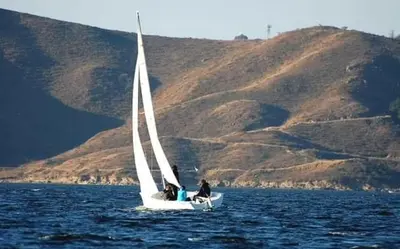 two people on a sail boat in the water at Minicasas cerca del rio Los Reartes in Villa Ciudad Parque