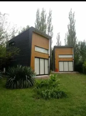 a house with two windows in a grass field at Minicasas cerca del rio Los Reartes in Villa Ciudad Parque