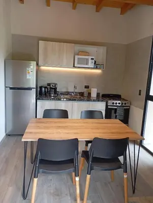 a kitchen with a wooden table and chairs and a refrigerator at Cabaña VenTeVeo Chakra de Montaña in Atos Pampa