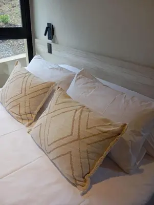 a bed with white sheets and pillows on it at Cabaña VenTeVeo Chakra de Montaña in Atos Pampa