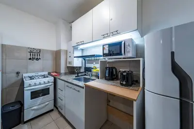 a kitchen with white cabinets and a sink and a refrigerator at Viaggiato Felix Frías in Cordoba