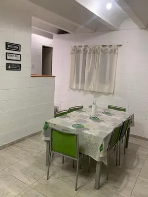 a room with a table with green chairs and a white table cloth at Casa Playas De Oro in Villa Independencia