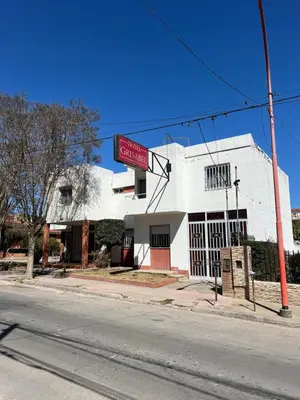a white building on the corner of a street at Hotel Grisabel in Villa Carlos Paz
