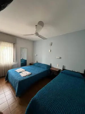 a bedroom with two beds and a ceiling fan at Hotel Grisabel in Villa Carlos Paz