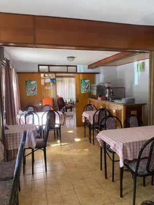 a dining room with tables and chairs and a kitchen at Hotel Grisabel in Villa Carlos Paz