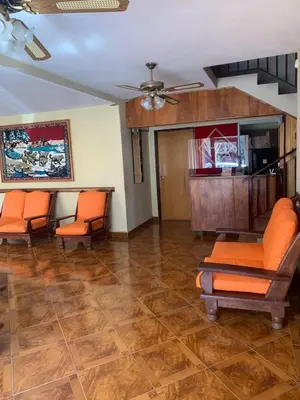 a living room with orange chairs and a ceiling fan at Hotel Grisabel in Villa Carlos Paz