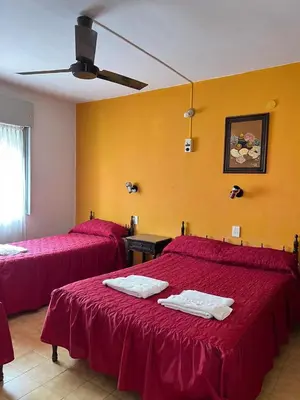 a hotel room with two beds with red sheets at Hotel Grisabel in Villa Carlos Paz