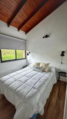 a bedroom with a large white bed with a wooden ceiling at Flusshaus8 in Villa General Belgrano