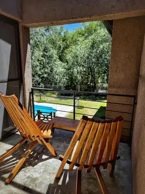two wooden benches sitting on a porch with a view of a park at Flusshaus8 in Villa General Belgrano
