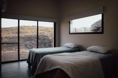 two beds in a room with two large windows at Cabaña en Tala Cruz a 9km de Villa Cañada del Sauce in Tala Cruz