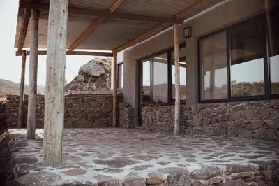 a building with windows and a stone wall at Cabaña en Tala Cruz a 9km de Villa Cañada del Sauce in Tala Cruz
