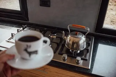a person holding a cup of coffee next to a stove at Cabaña en Tala Cruz a 9km de Villa Cañada del Sauce in Tala Cruz