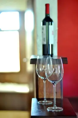 two wine glasses sitting on a table with a bottle of wine at Senderos del Tao in Las Rabonas