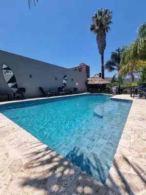 a swimming pool at a resort with a palm tree at Hotel Posada del Ángel in Villa Carlos Paz