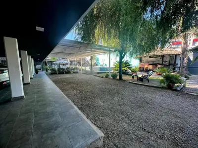 a building with a walkway next to a park with benches at Hotel Posada del Ángel in Villa Carlos Paz