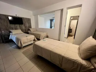 a hotel room with two beds and a flat screen tv at Hotel Posada del Ángel in Villa Carlos Paz