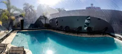 a swimming pool with chairs next to a building at Hotel Posada del Ángel in Villa Carlos Paz