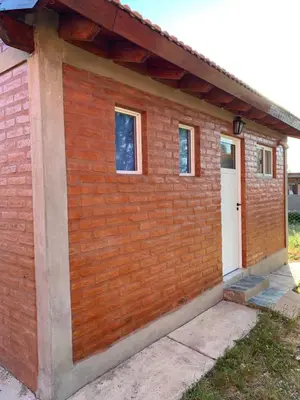 a red brick building with a white door at Cabañas Rosarito in Villa Larca