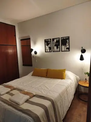 a bedroom with a bed with three pictures on the wall at Funes Departamento céntrico un dormitorio Solo turistas in Cordoba