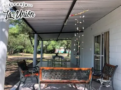 a porch with a bench and a table and chairs at Granja La Unión in Villa Dolores