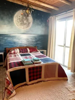 a bedroom with a bed with a painting of the moon at Casita Sirio in Mina Clavero