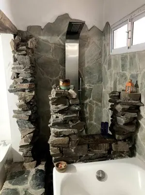 a bathroom with a stone wall and a bath tub at Casita Sirio in Mina Clavero