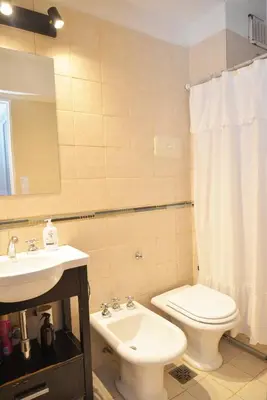 a bathroom with a white toilet and a sink at Departamento lindo y cálido in Cordoba