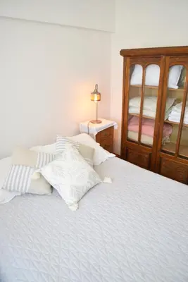 a bedroom with a white bed with a wooden cabinet at Departamento lindo y cálido in Cordoba