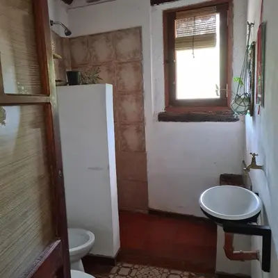 a bathroom with a toilet and a sink and a window at Casa de Monte in Cerro de Oro