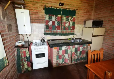 a kitchen with a stove and a refrigerator at El Viejo Molino Casas de Campo in Nono