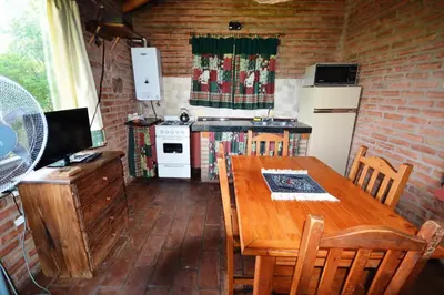 a kitchen with a wooden table with chairs and a refrigerator at El Viejo Molino Casas de Campo in Nono