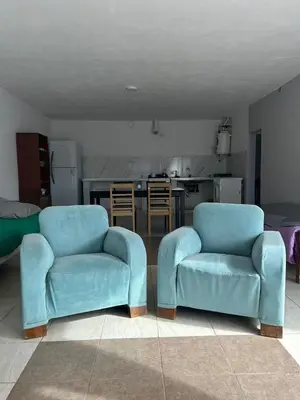 two blue chairs in a living room with a kitchen at Depto1 in Río Cuarto