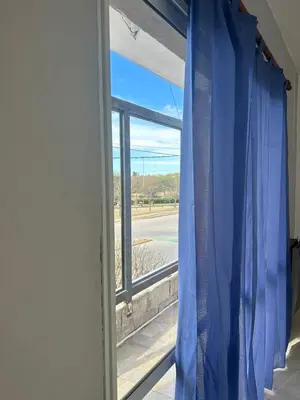 a window with a blue curtain in a room at Depto1 in Río Cuarto