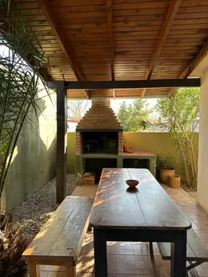 a picnic table under a wooden roof with a pizza oven at Casa López en el centro de Santa Rosa de Calamuchita in Santa Rosa de Calamuchita