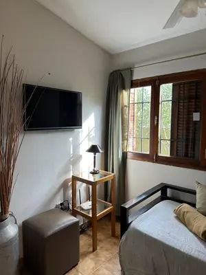 a bedroom with a bed and a tv on the wall at Casa López en el centro de Santa Rosa de Calamuchita in Santa Rosa de Calamuchita
