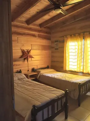 a bedroom with two beds in a log cabin at Los Grillos Cabañas Serranas in Los Reartes