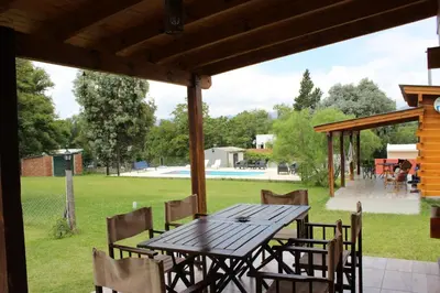 a wooden table and chairs on a patio at Los Grillos Cabañas Serranas in Los Reartes