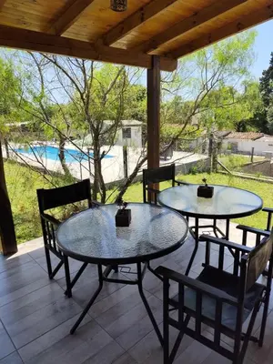 two tables and chairs on a porch with a pool at Los Grillos Cabañas Serranas in Los Reartes