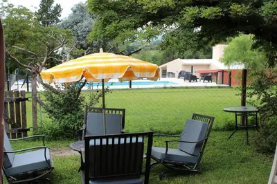 a group of chairs and a table with an umbrella at Los Grillos Cabañas Serranas in Los Reartes