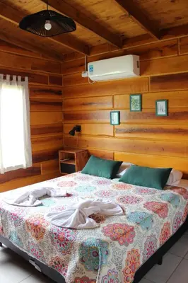 a bedroom with a bed in a room with wooden walls at Los Grillos Cabañas Serranas in Los Reartes