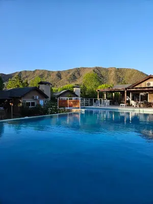 a large pool of blue water with mountains in the background at Las Lechuzas Complejo in Santa Rosa de Calamuchita