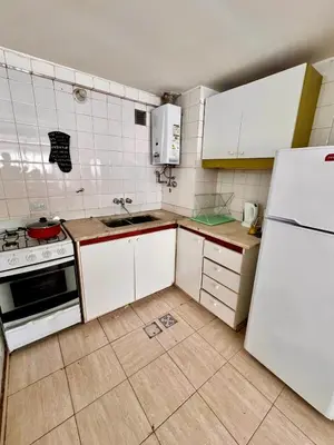 a kitchen with white cabinets and a white refrigerator at Departamentos Refugio del Rio in Cordoba