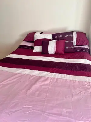 a bed with purple and white sheets and pillows at Departamentos Refugio del Rio in Cordoba