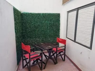 a table and two chairs in front of a green wall at TREJO APART, A 40MTS DEL PATIO OLMOS, PLANTA BAJA in Cordoba
